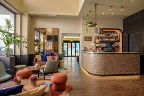 Zona de bar moderna con mostrador curvo, asientos con cojines coloridos y varias plantas.