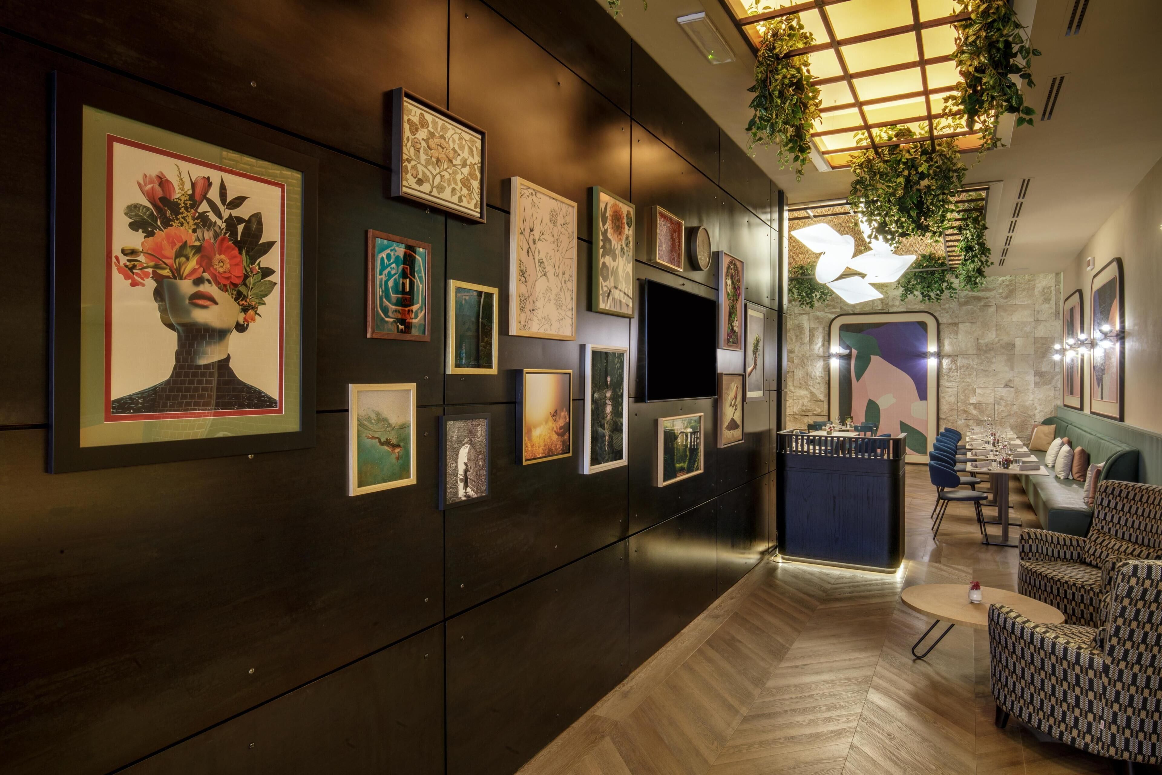 Un corridoio con opere d'arte alle pareti, un'area salotto con un tavolo e una scala che conduce a un altro livello.
