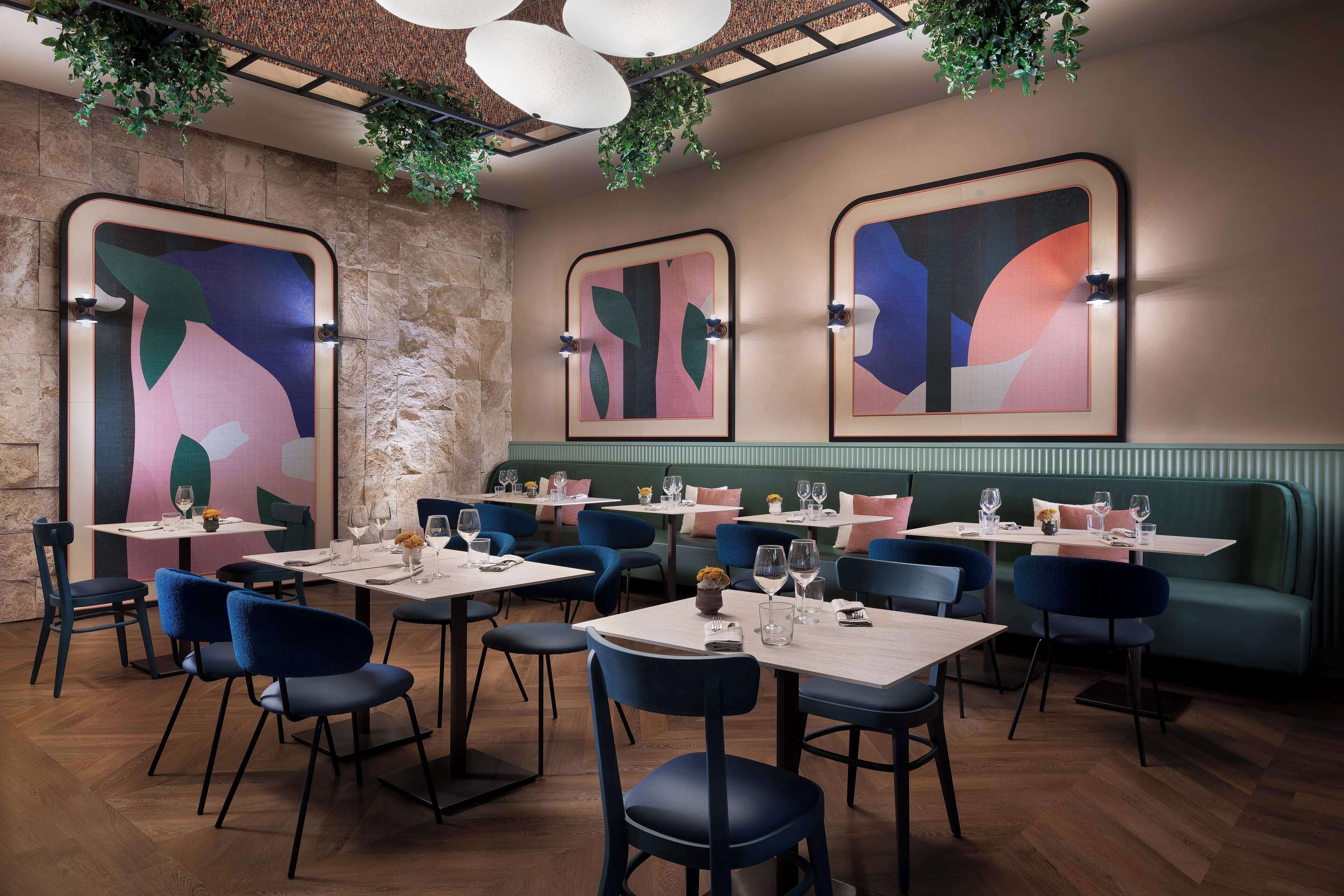 Interno di un ristorante con tavoli, sedie e arte astratta alle pareti.