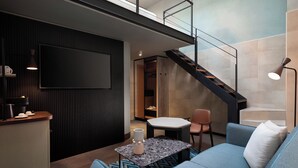 A modern living room with a sofa, a coffee table, and a TV mounted on the wall. - The Spring House Hotel Rome Vatican, Tapestry Collection Hilton (Rome)