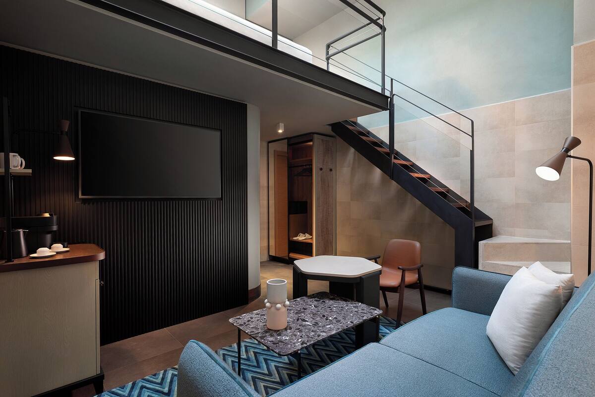 A modern living room with a sofa, a coffee table, and a TV mounted on the wall.