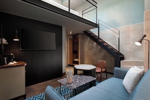 A modern living room with a sofa, a coffee table, and a TV mounted on the wall. - The Spring House Hotel Rome Vatican, Tapestry Collection Hilton (Rome)