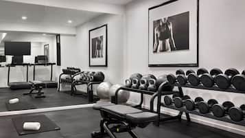 A modern gym with exercise equipment, a treadmill, and motivational posters on the walls.