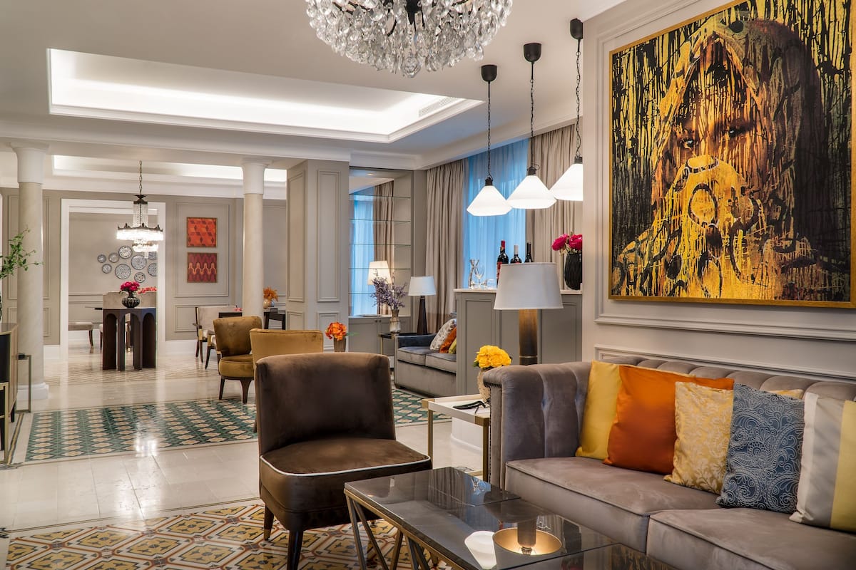 A spacious living area with a modern chandelier, a large abstract painting, and a comfortable seating arrangement.