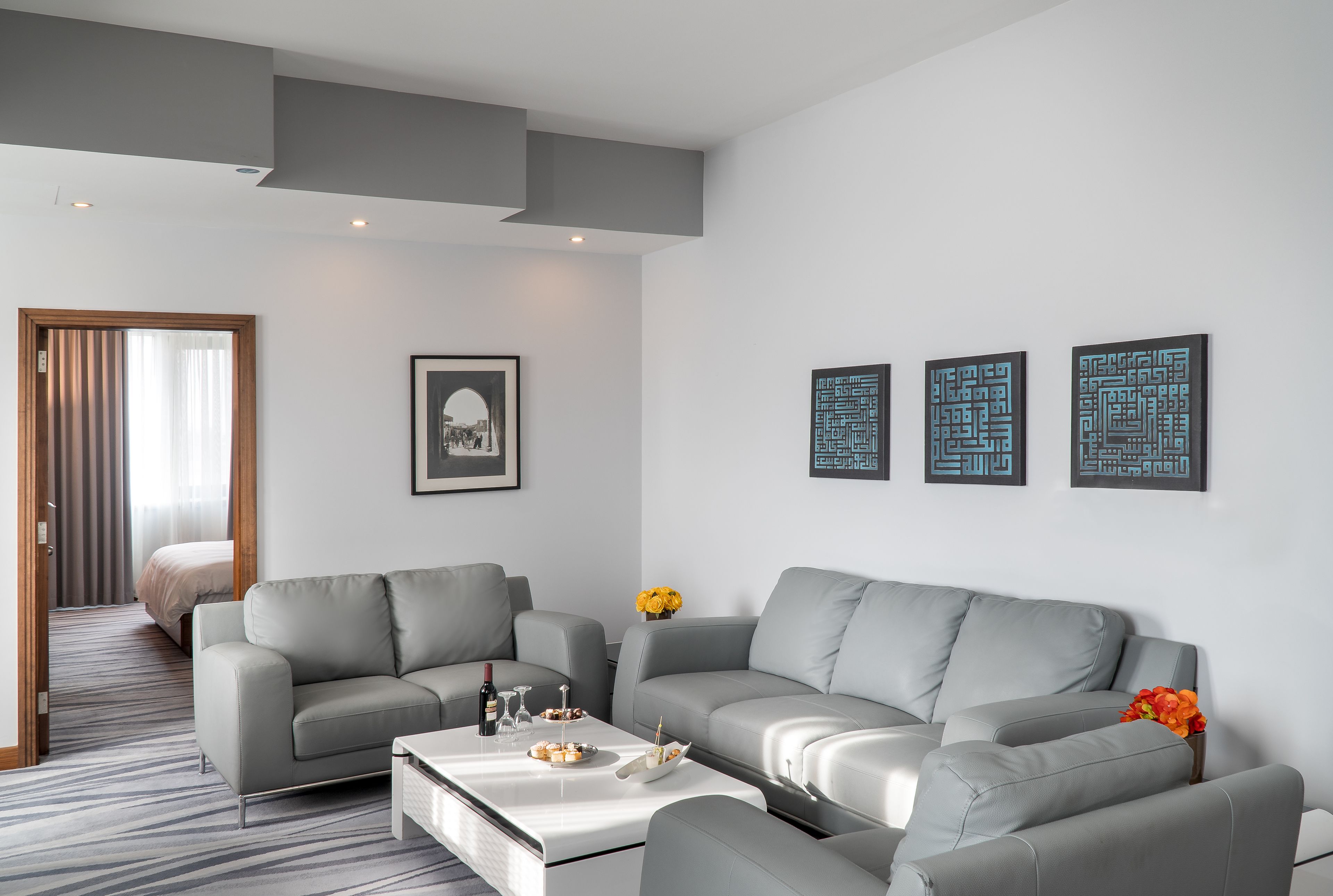 A modern living room with grey sofas, a coffee table, and artwork on the wall.