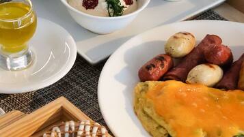 A breakfast buffet with various dishes including eggs, sausages, and pastries.