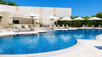 Una piscina al aire libre de temporada, sombrillas