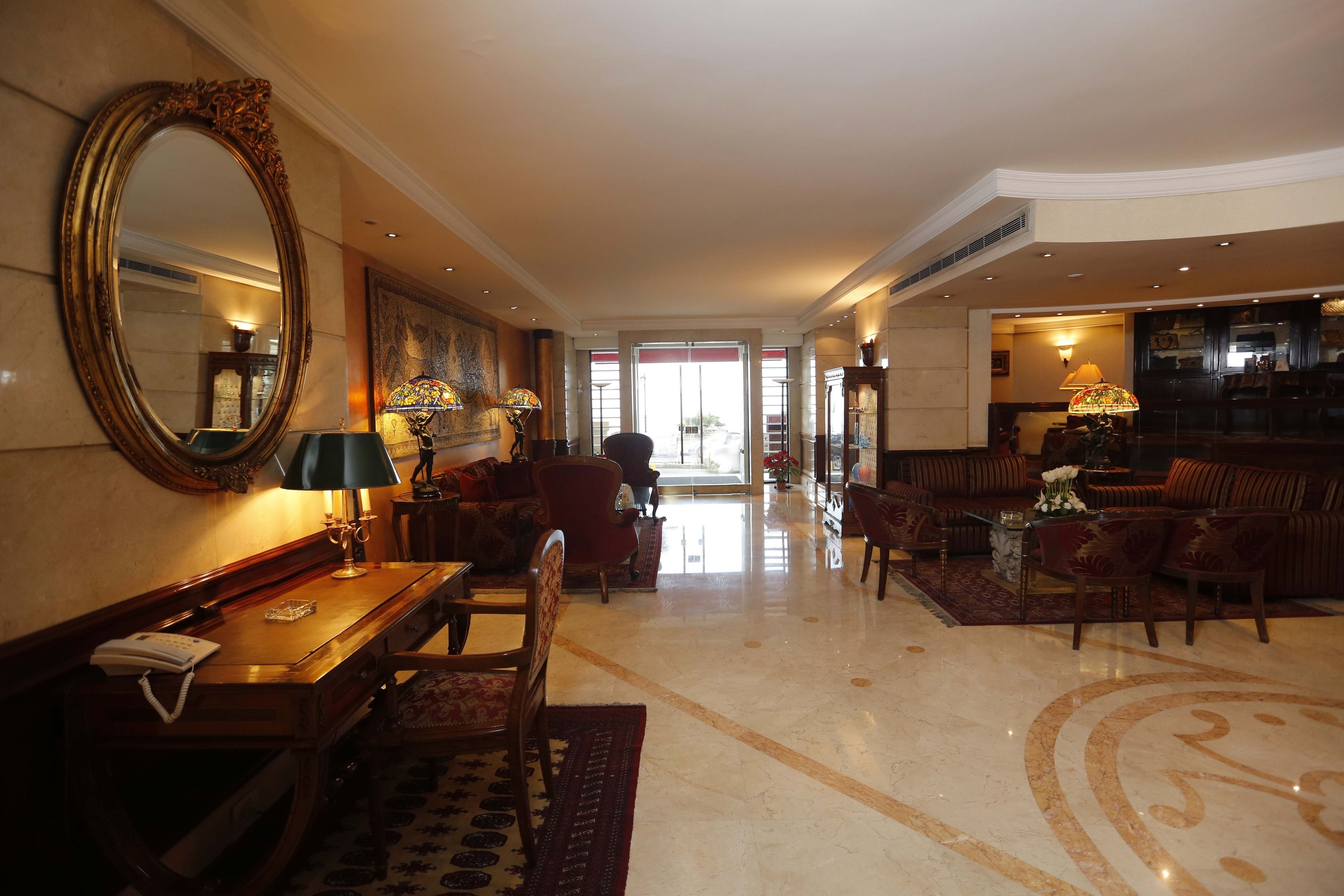 A spacious lobby with a grand mirror, comfortable seating, and a well-lit entrance.