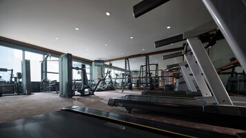 Et fitnesscenter med løbebånd, træningsmaskiner og et spejl.