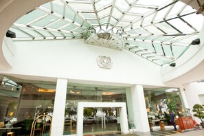 Un edificio moderno con techo de vidrio y un emblema central.