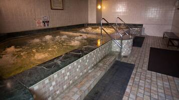 A hot tub with a tiled floor and a metal railing.