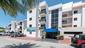 A multi-story hotel with balconies, a blue awning, and a parked vehicle. - Hotel Imperial Laguna Faranda (Cancun)