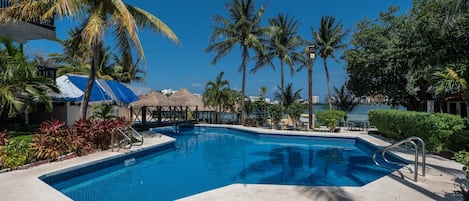 Una piscina al aire libre, sillones reclinables de piscina