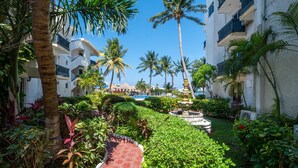 A lush garden with palm trees and a red pathway leading to a pool area. - Hotel Imperial Laguna Faranda (Cancun)