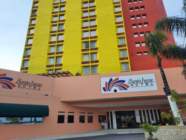 A multi-story hotel with a yellow and red facade, featuring the Santa Irene Hotel sign.