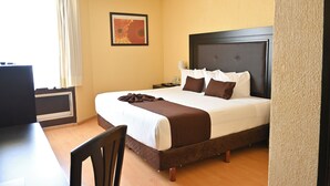 A hotel room with a bed, a desk, and a chair.