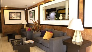 A modern living room with a grey sofa, two black side tables, and a glass coffee table.