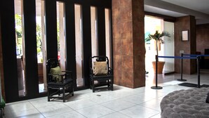 A lobby with two black armchairs, a large tufted sofa, and a blue barrier.