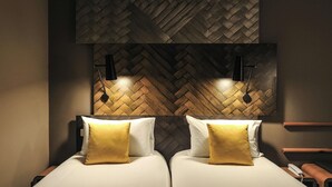 Une chambre d’hôtel avec deux lits, un mur orné d’un motif en chevrons et un téléphone fixé au mur.