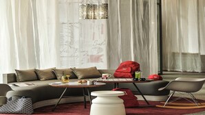 Un salon moderne avec un canapé, une table basse, un sac rouge et un fauteuil à bascule.