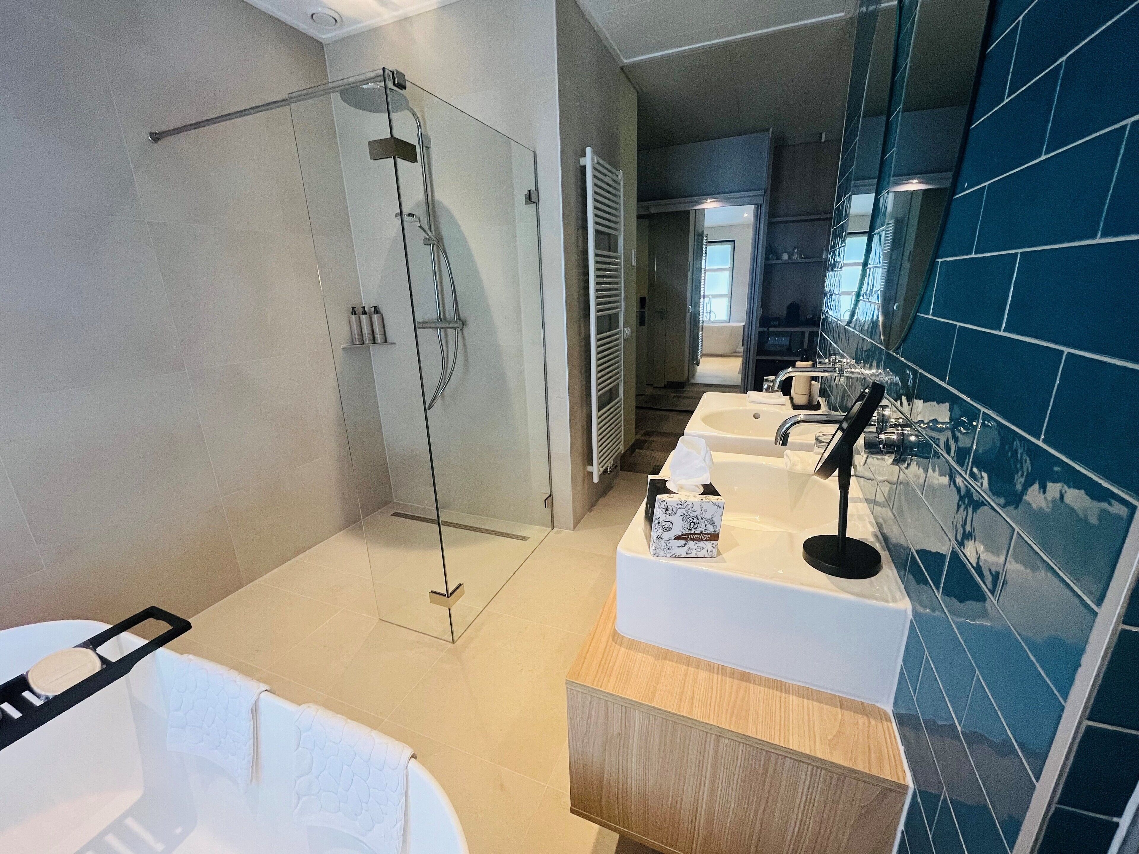 A modern bathroom with a glass-enclosed shower, a bathtub, and a vanity with a mirror and sink.