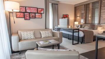 A modern hotel room with a sofa, a coffee table, a desk, and a bed.
