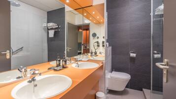 Ein modernes Badezimmer mit drei Waschbecken, einer Toilette und einer Dusche.
