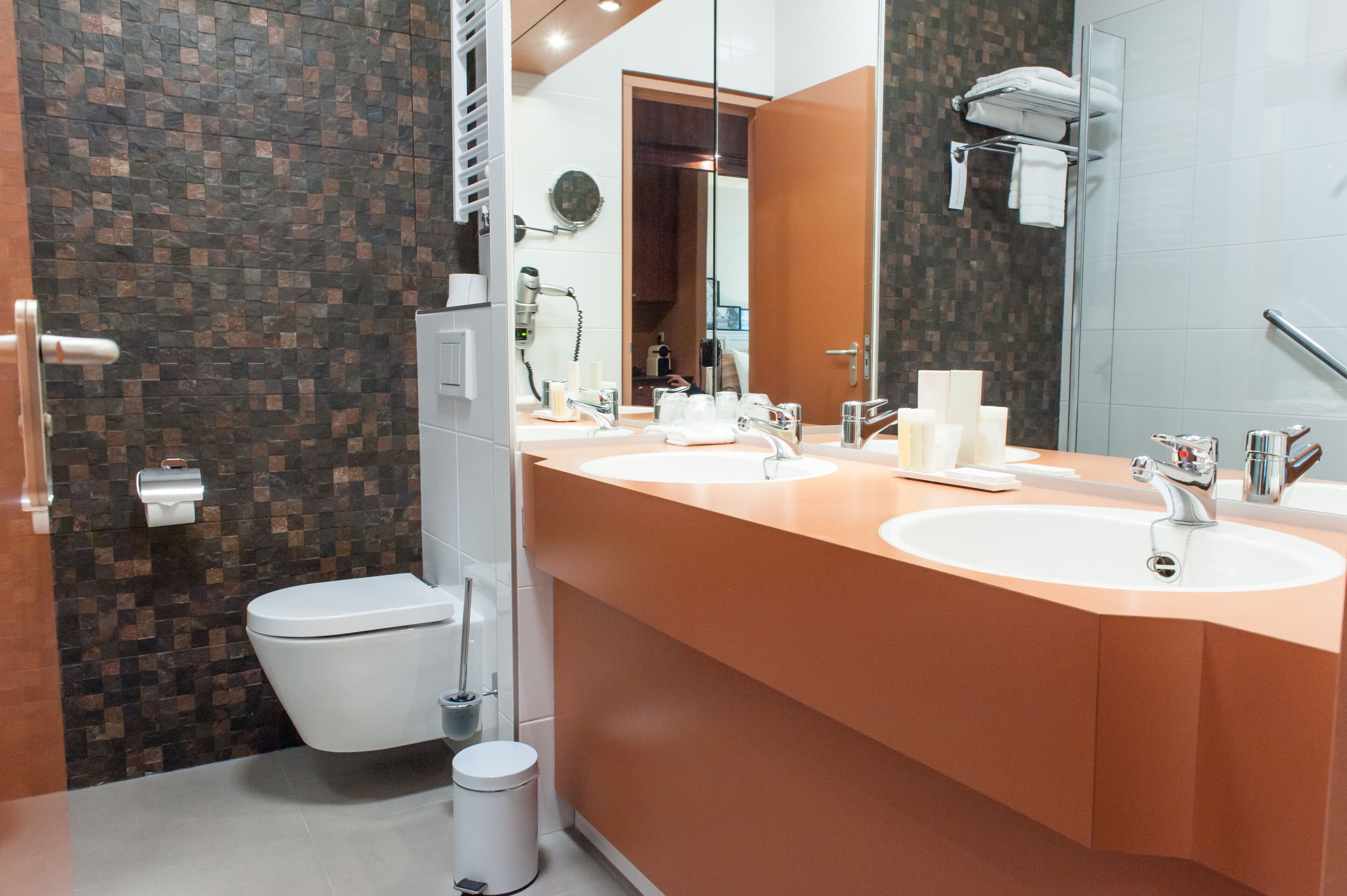 A modern bathroom with two sinks, a toilet, and a shower area.