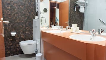 A modern bathroom with two sinks, a toilet, and a shower area.