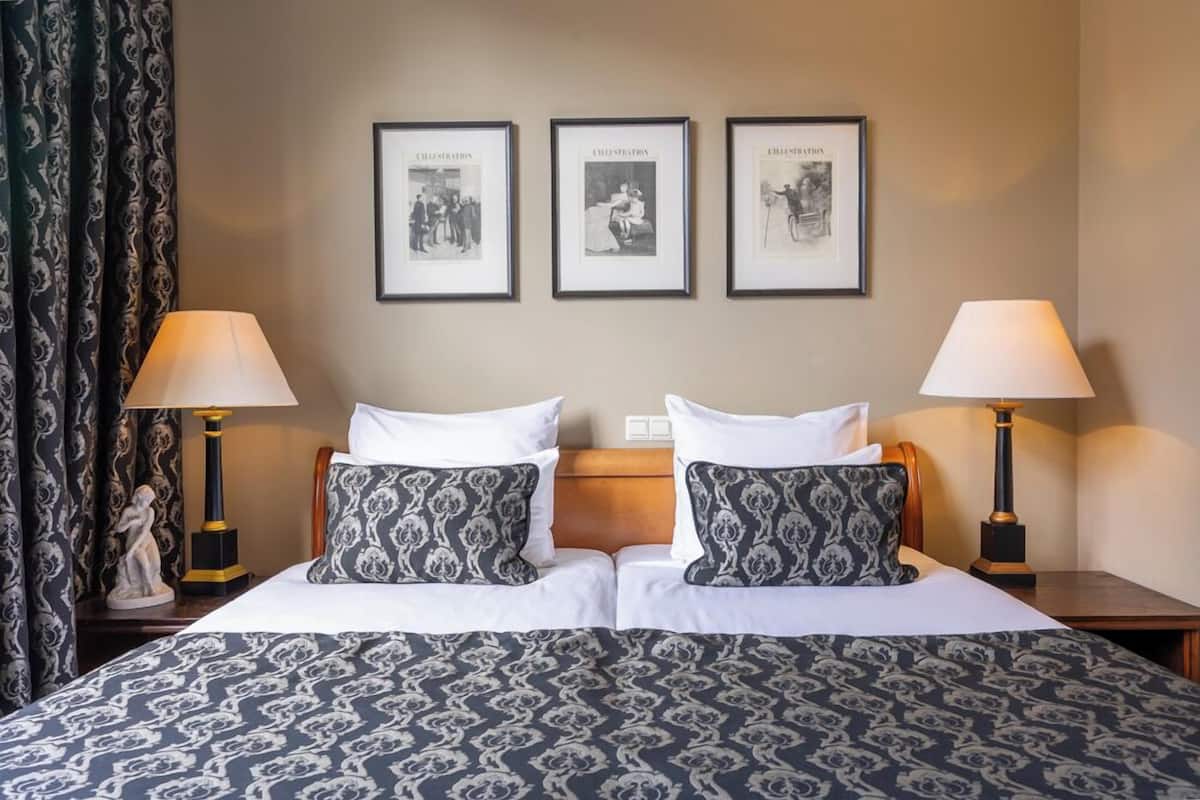 Un lit double avec une literie à motifs, deux lampes de chevet et trois tableaux encadrés accrochés au mur.