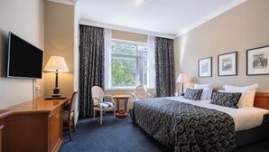 Een hotelkamer met een bed, bureau, stoel en een televisie.