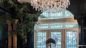 Une chambre luxueuse, ornée d’un lustre, comprenant deux fauteuils confortables, une petite table et une grande fenêtre offrant une vue imprenable.