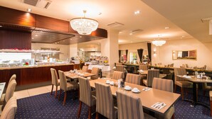 A hotel dining area with multiple tables and chairs, a buffet counter, and a chandelier. - Scenic Hotel Southern Cross (Dunedin)