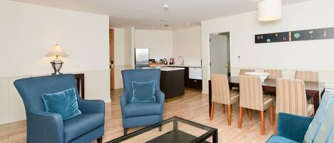 A modern living room with a sofa, two armchairs, a coffee table, and a dining area with chairs and a table.