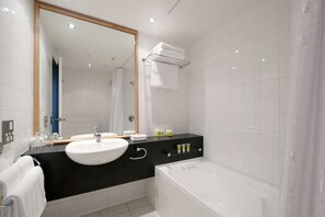 A modern bathroom with a white sink, black countertop, and a white bathtub. - Scenic Hotel Southern Cross (Dunedin)