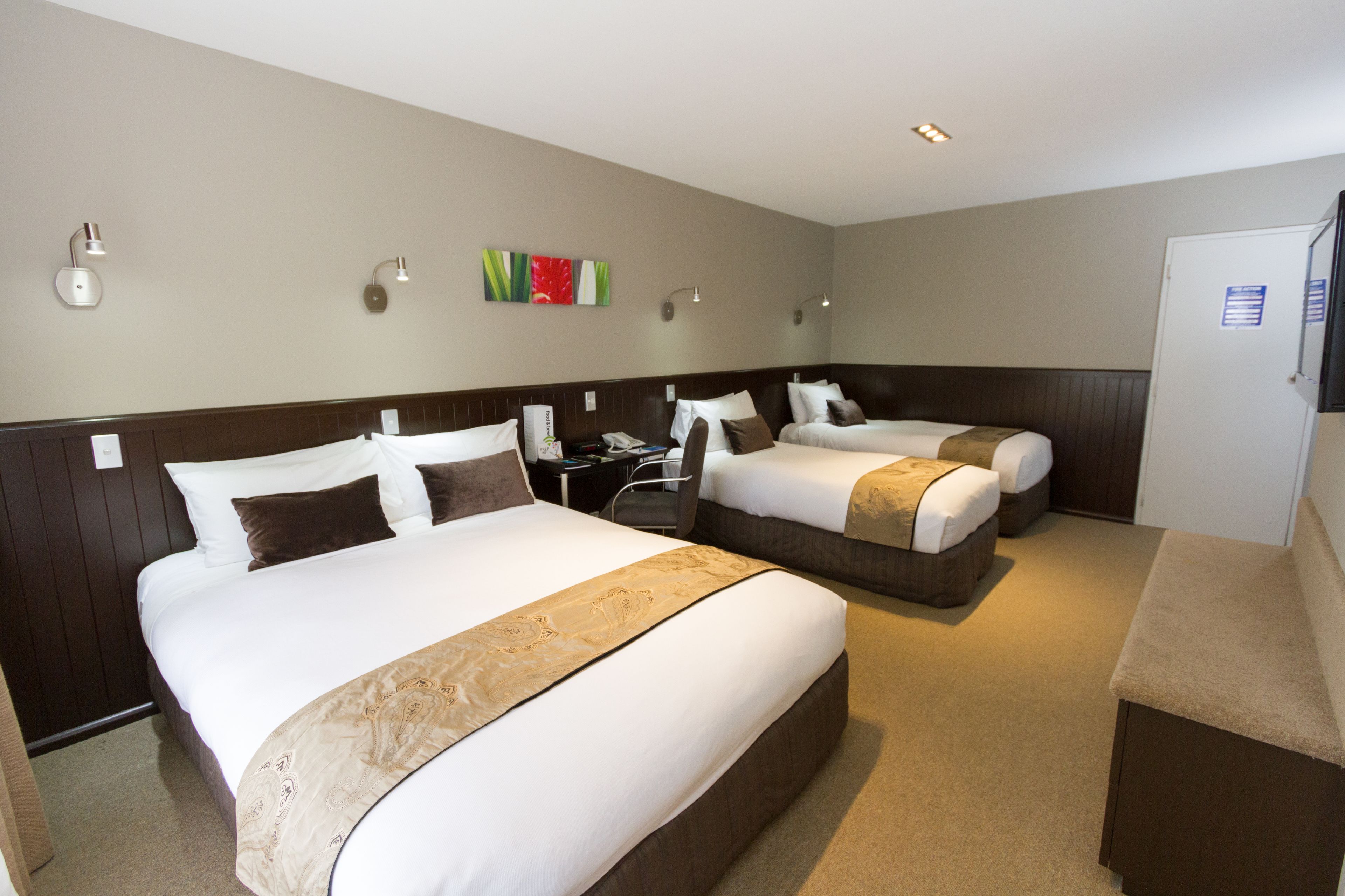 Une chambre d’hôtel avec deux lits, un bureau et un petit coin salon.