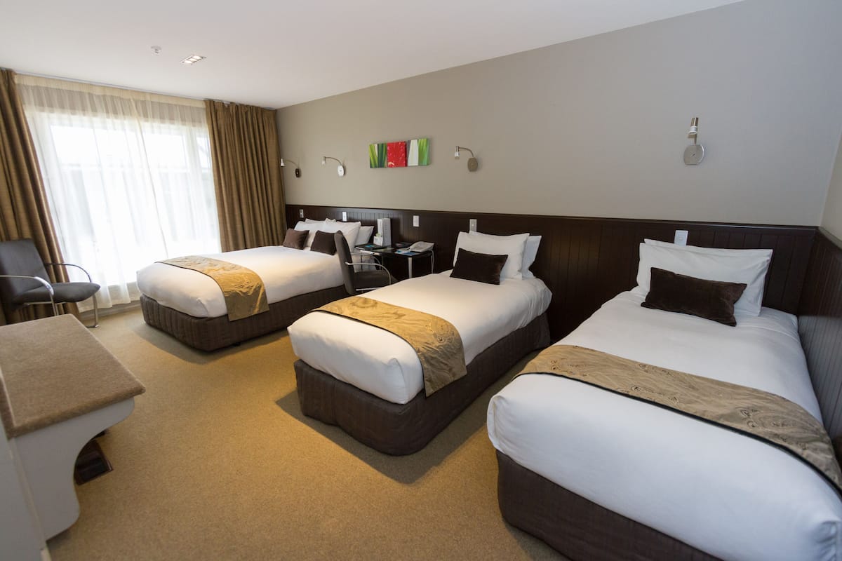 Habitación de hotel con dos camas, un escritorio y una silla.