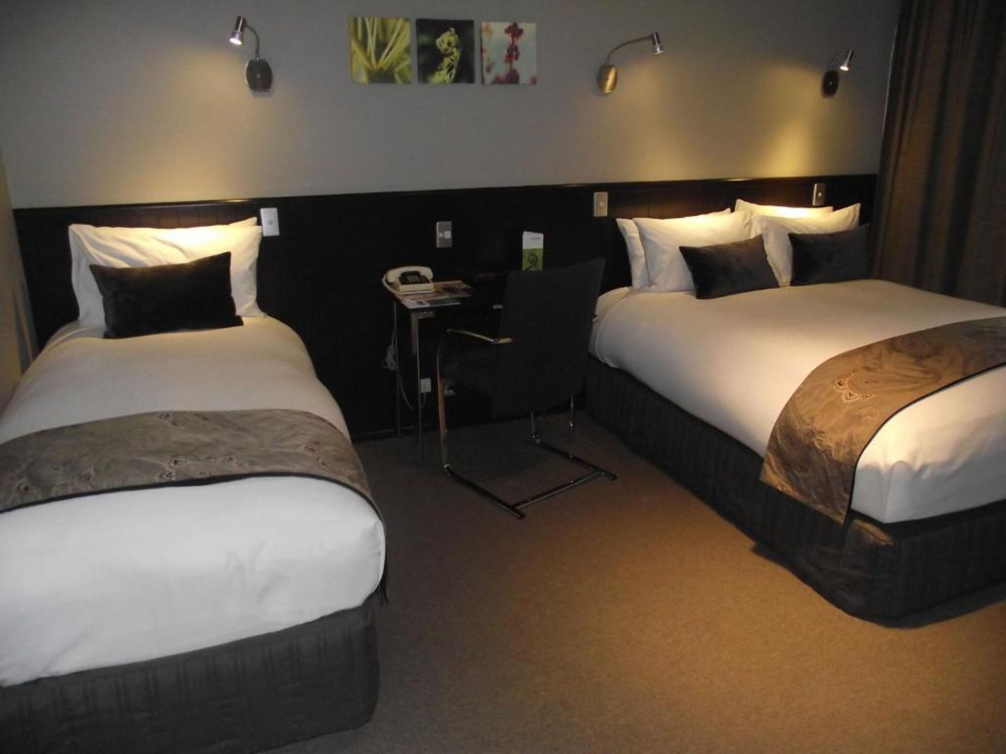 A hotel room with two beds, a desk, and a chair.