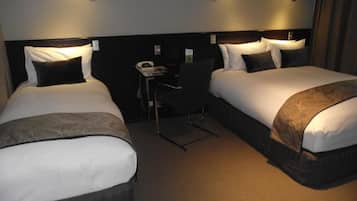 A hotel room with two beds, a desk, and a chair.