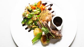 A plate of food with various vegetables and a piece of meat, accompanied by a small bowl of sauce.