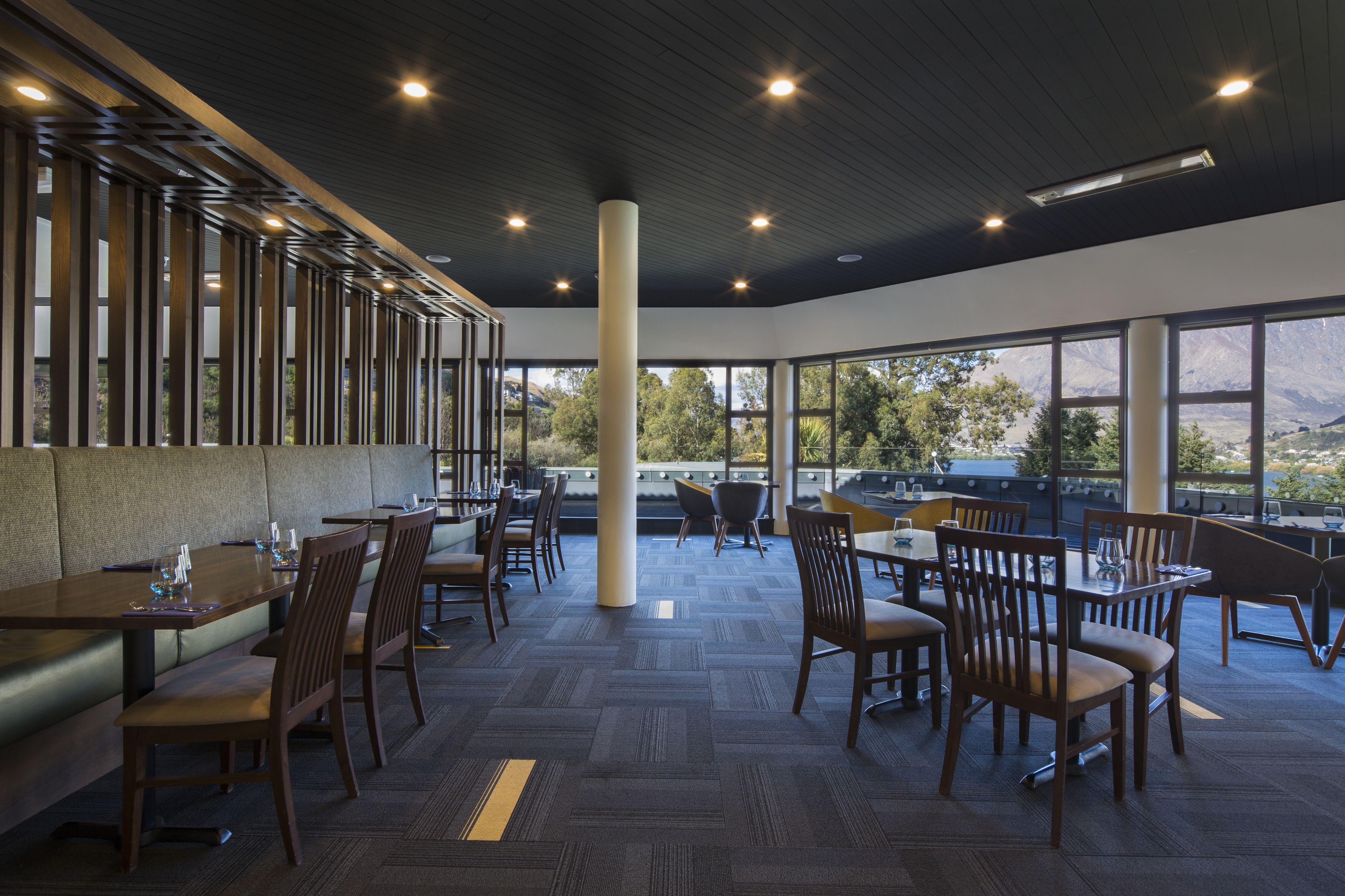 Un restaurant spacieux avec de hauts plafonds, de grandes fenêtres et une vue sur les montagnes.