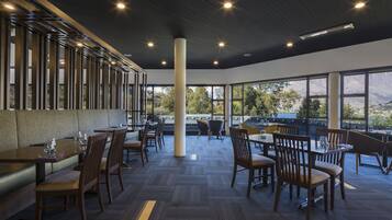 Un restaurant spacieux avec de hauts plafonds, de grandes fenêtres et une vue sur les montagnes.