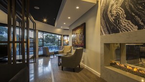 A modern interior with a fireplace, seating area, and large windows offering views of the outdoors. - Holiday Inn Queenstown Frankton Road by IHG (Queenstown)