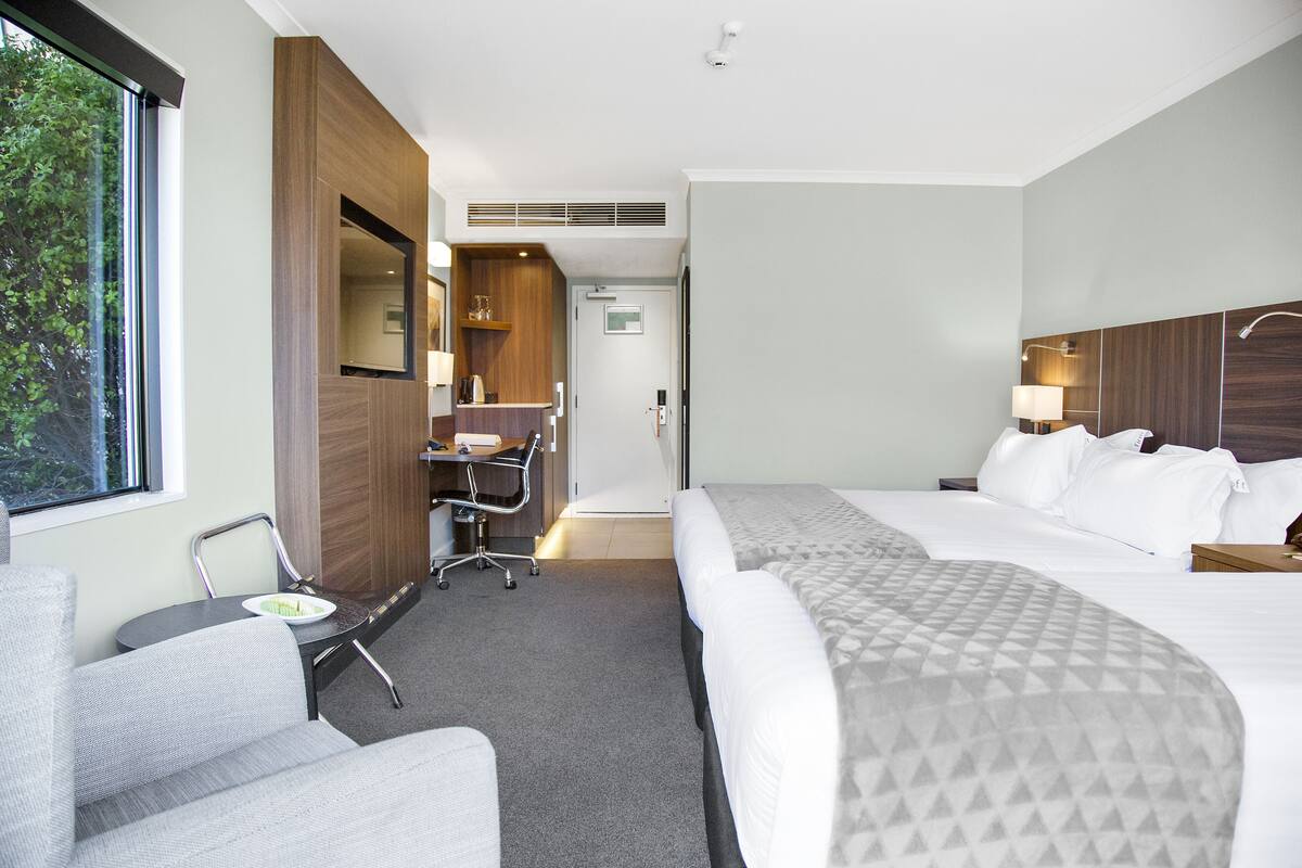 A hotel room with a bed, a desk, a chair, and a window.