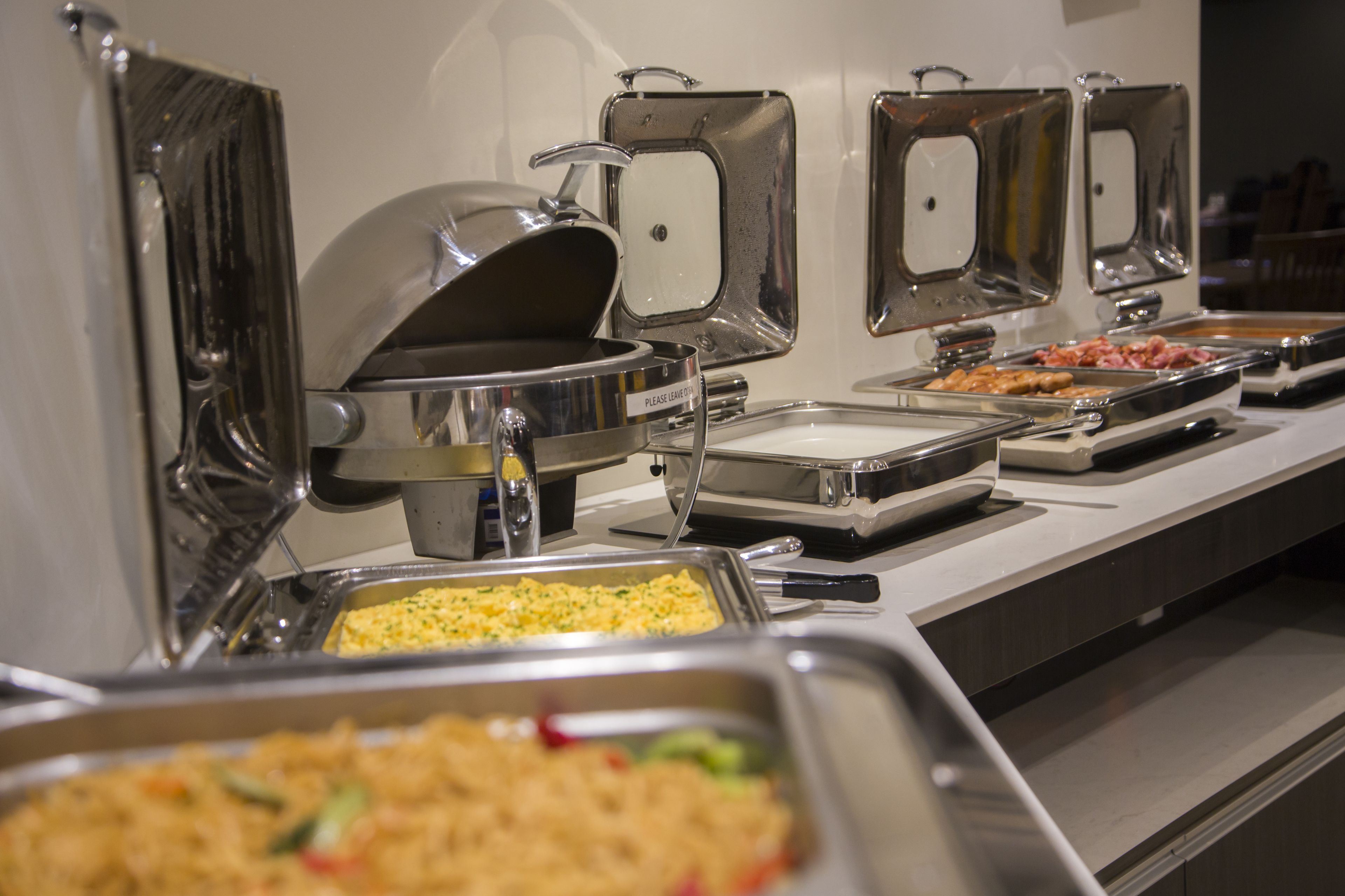 Un bufé con diversos alimentos presentados en fuentes de metal.