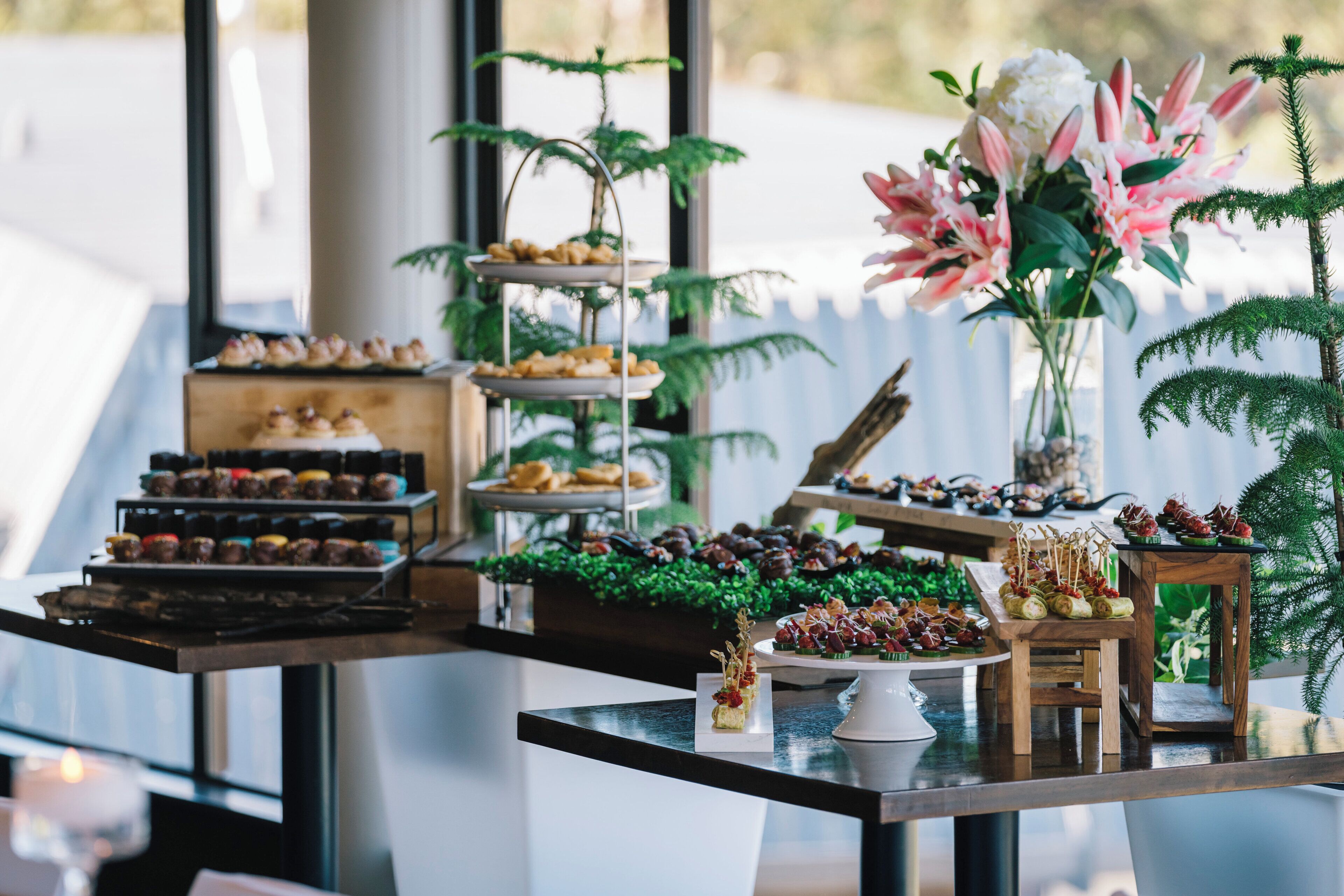 A buffet table with various food items and a floral centerpiece.