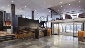 Un hall espacioso con suelo de cuadros, una escalera y una zona de estar con vistas al exterior.
