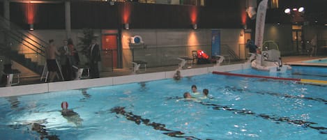 A swimming pool with lanes, a lifeguard stand, and a seating area with chairs.