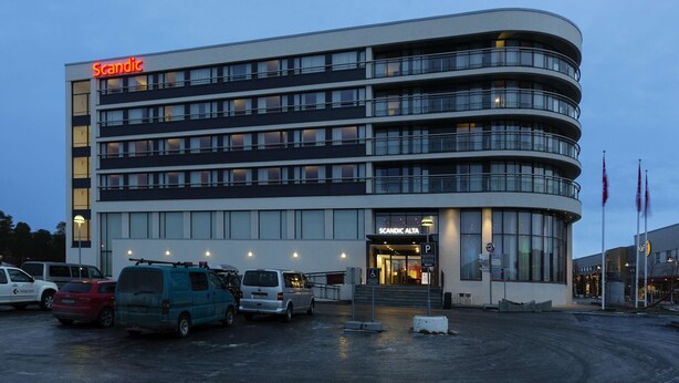A modern building with a curved facade, multiple floors, and a prominent entrance.