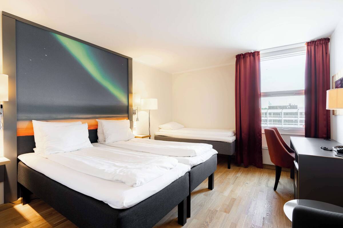 A hotel room with a large bed, a smaller bed, a desk, and a chair.